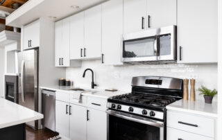 A white kitchen with stainless steel appliances, Cleaning Painted Cabinets Properly, preventing paint wear on cabinets